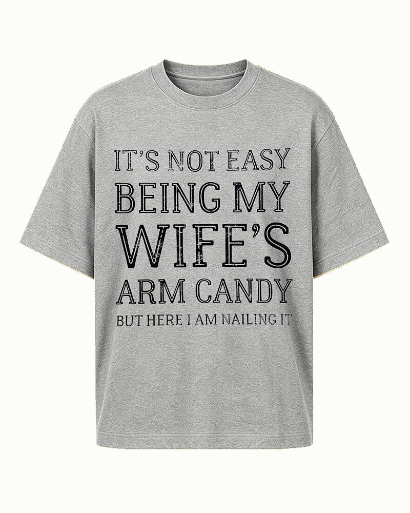 It's Not Easy Being My Wife's Arm Candy, but Here I Am Nailing It quote on Apricot cotton T-shirt