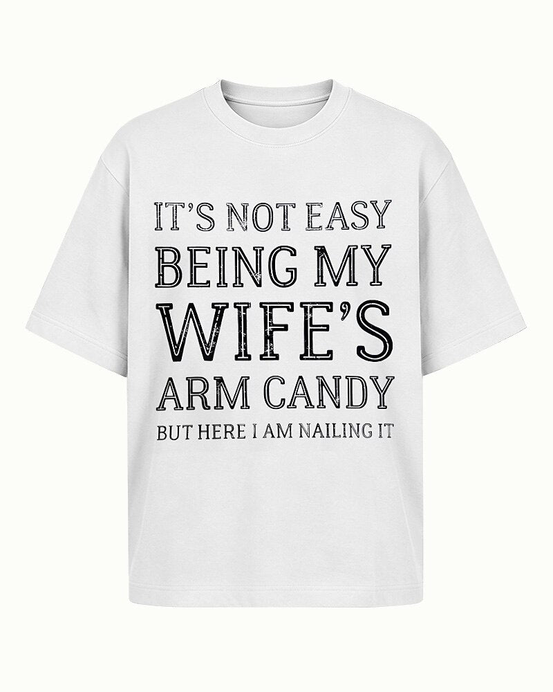 It's Not Easy Being My Wife's Arm Candy, but Here I Am Nailing It quote on Apricot cotton T-shirt