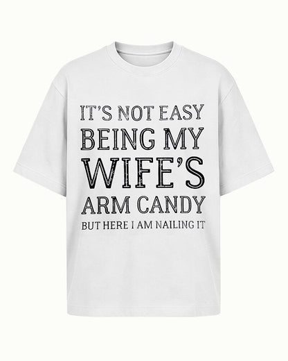 It's Not Easy Being My Wife's Arm Candy, but Here I Am Nailing It quote on Apricot cotton T-shirt